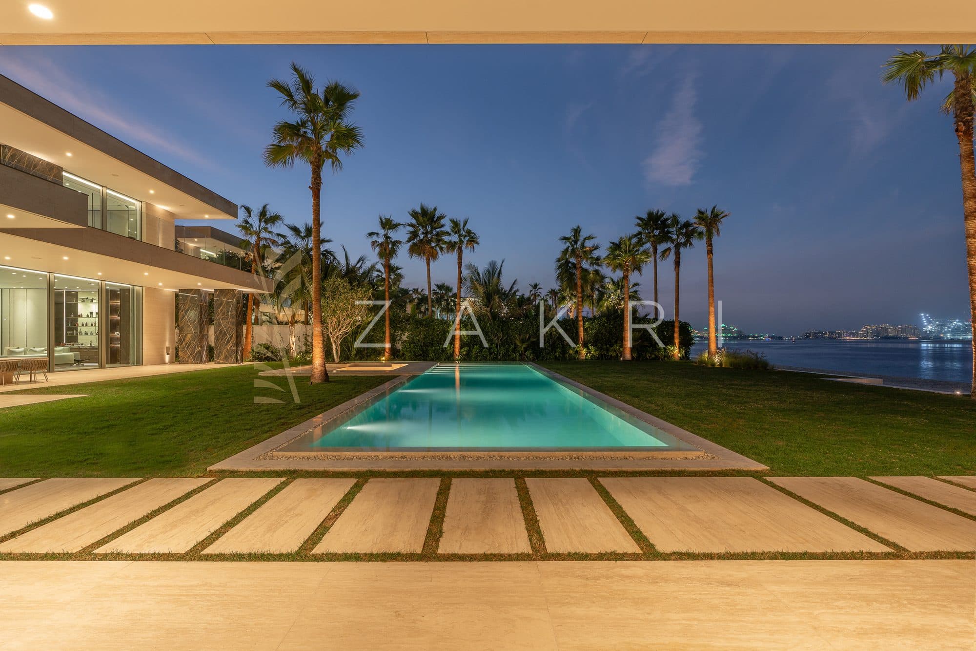 The pool and lawn at dusk, with the sea beyond